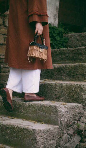 woman holding a wicker bag walking up the steps