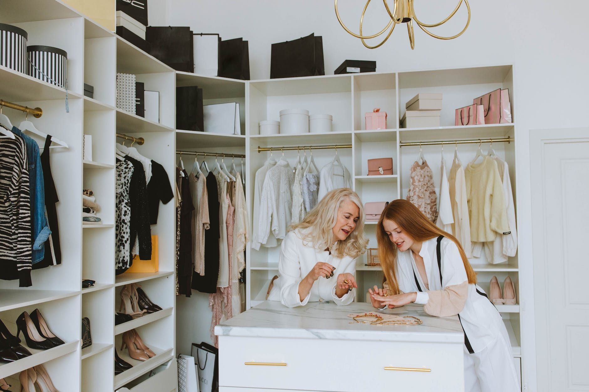 woman in white and girl with ginger hair looking at the jewelry on drawer in the wardrobe