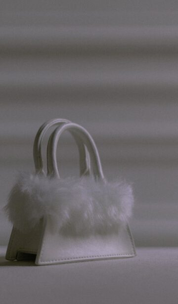 a white small bag with fur on a white surface