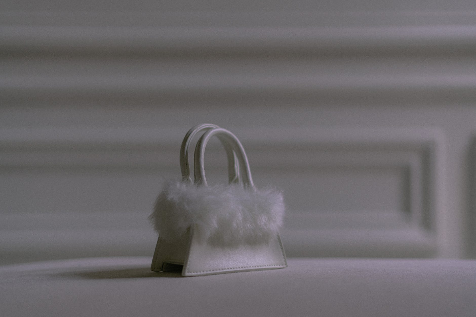 a white small bag with fur on a white surface Handtaschen Styles