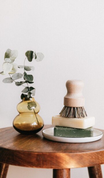soaps with shaving brush near vase on wooden table