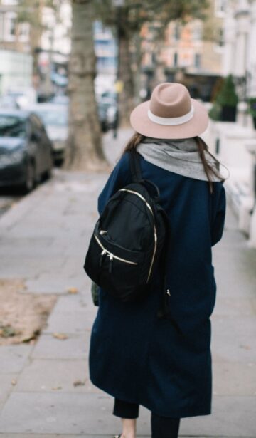 anonymous woman strolling on sidewalk in city district